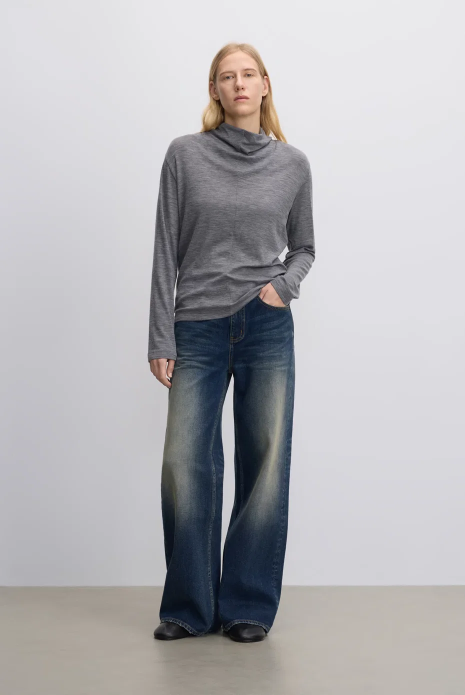 Fitted grey mock-neck top with blue wide-leg jeans.
