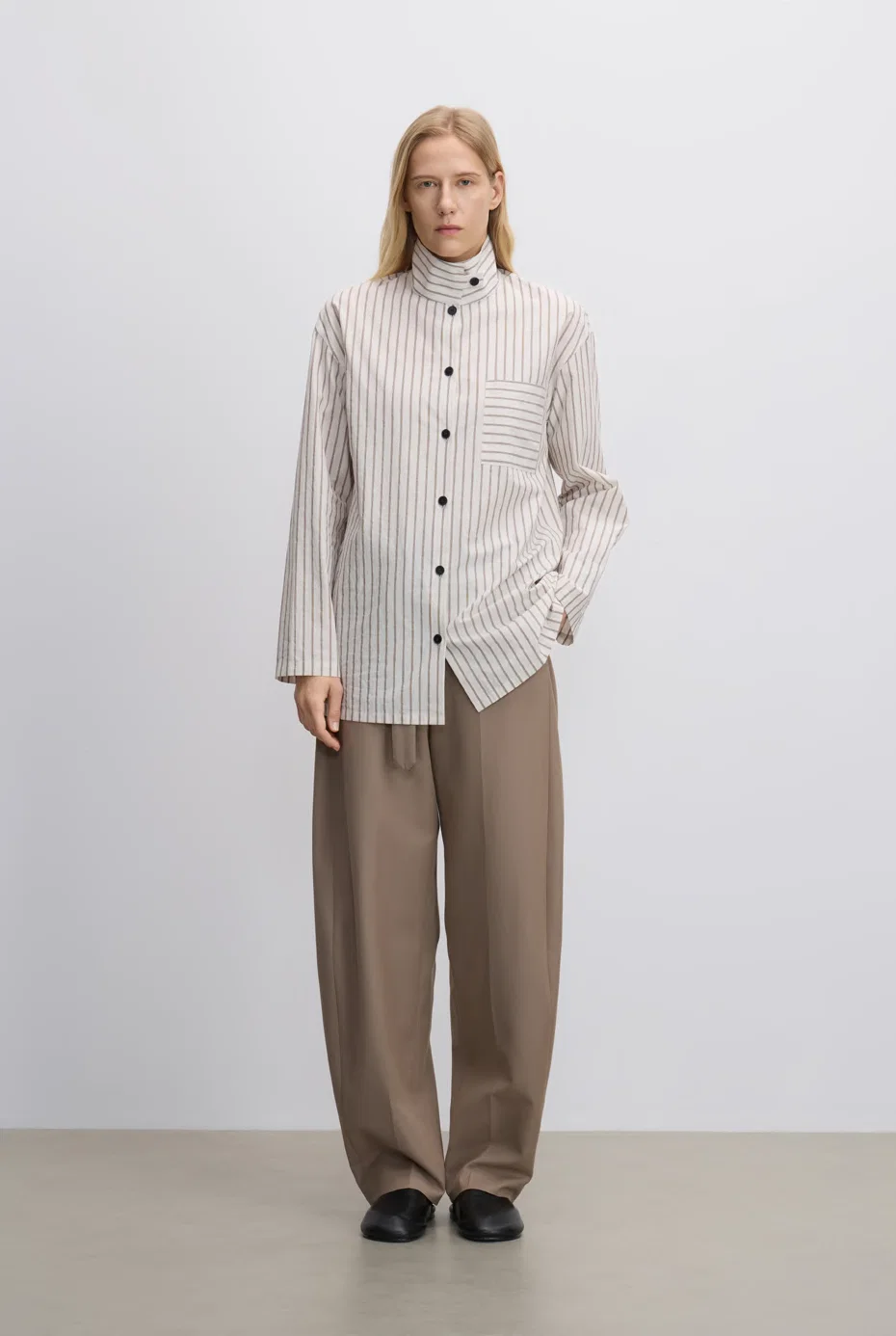 Ivory striped stand-collar shirt with taupe trousers.