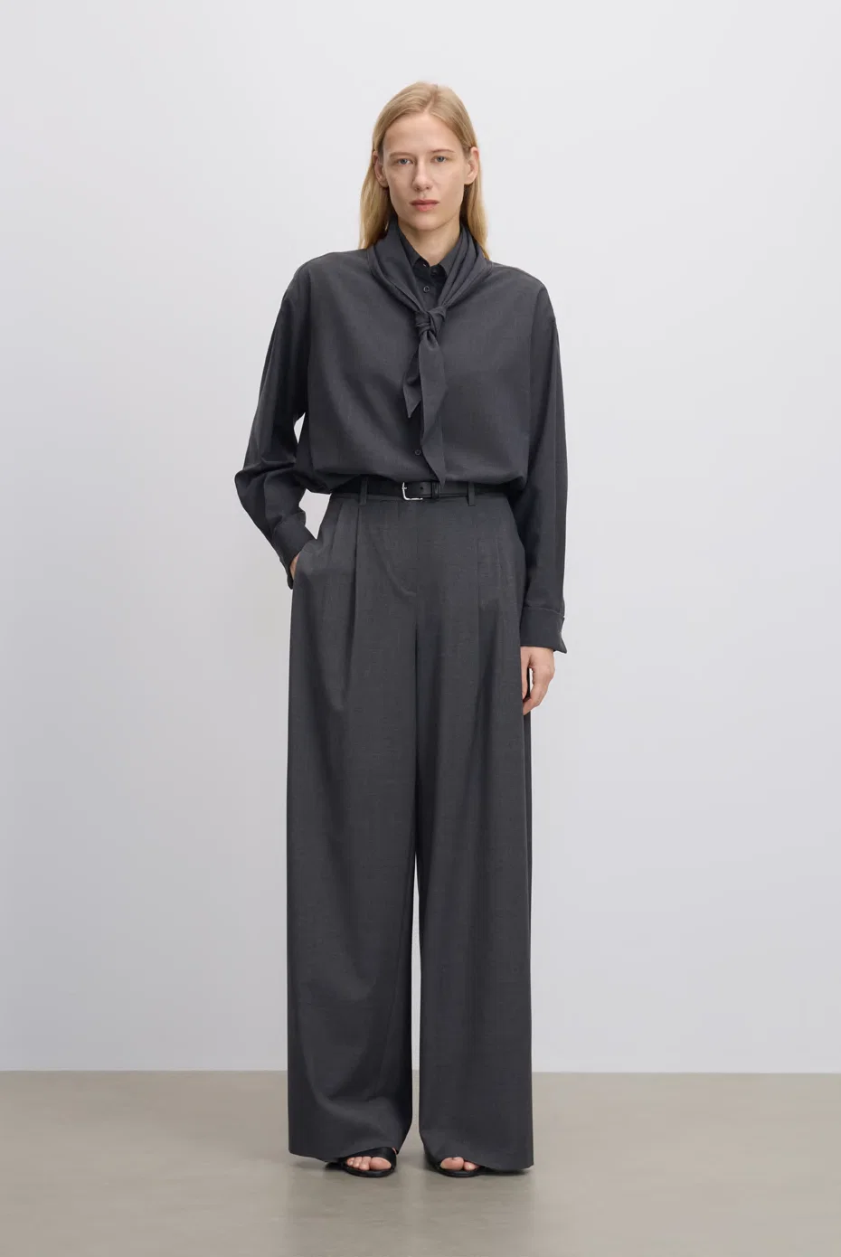 Charcoal scarf-neck blouse with tailored grey trousers.