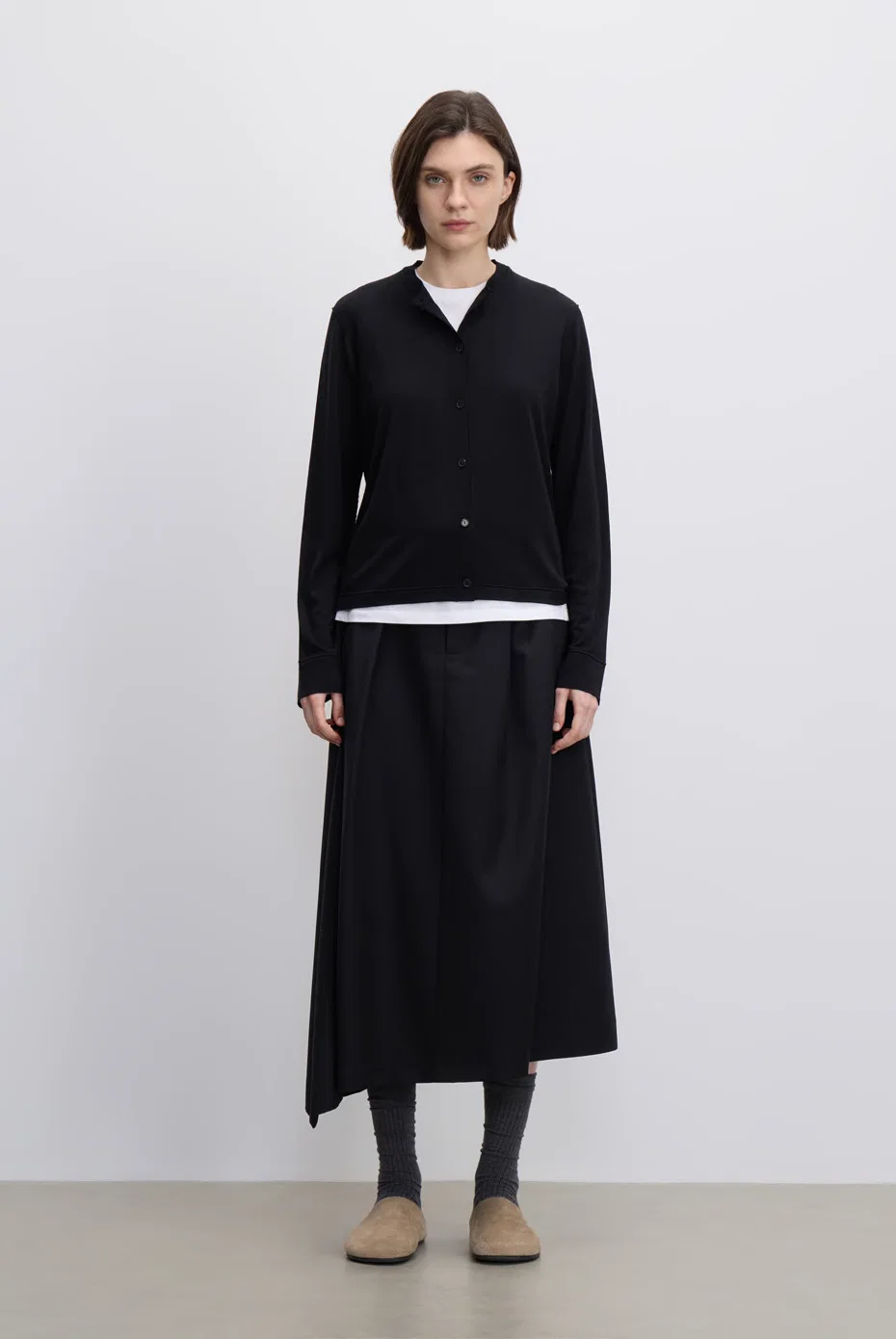 Black cropped jacket over an ivory blouse with a black midi skirt.