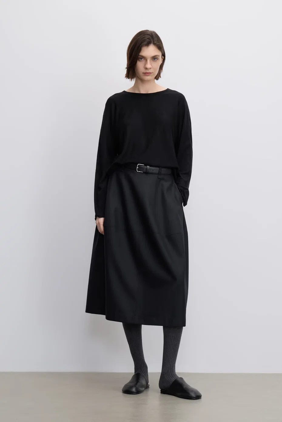Black boat-neck knit with a draped black midi skirt.