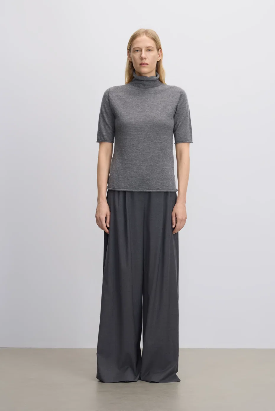 Grey short-sleeve mock-neck knit with grey wide-leg trousers.