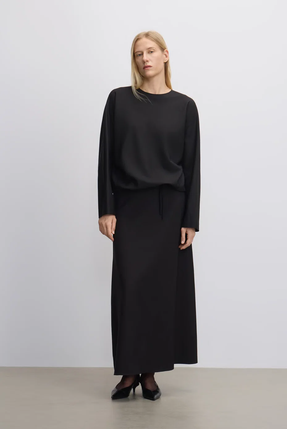 Black long-sleeve top with a fluid black midi skirt.