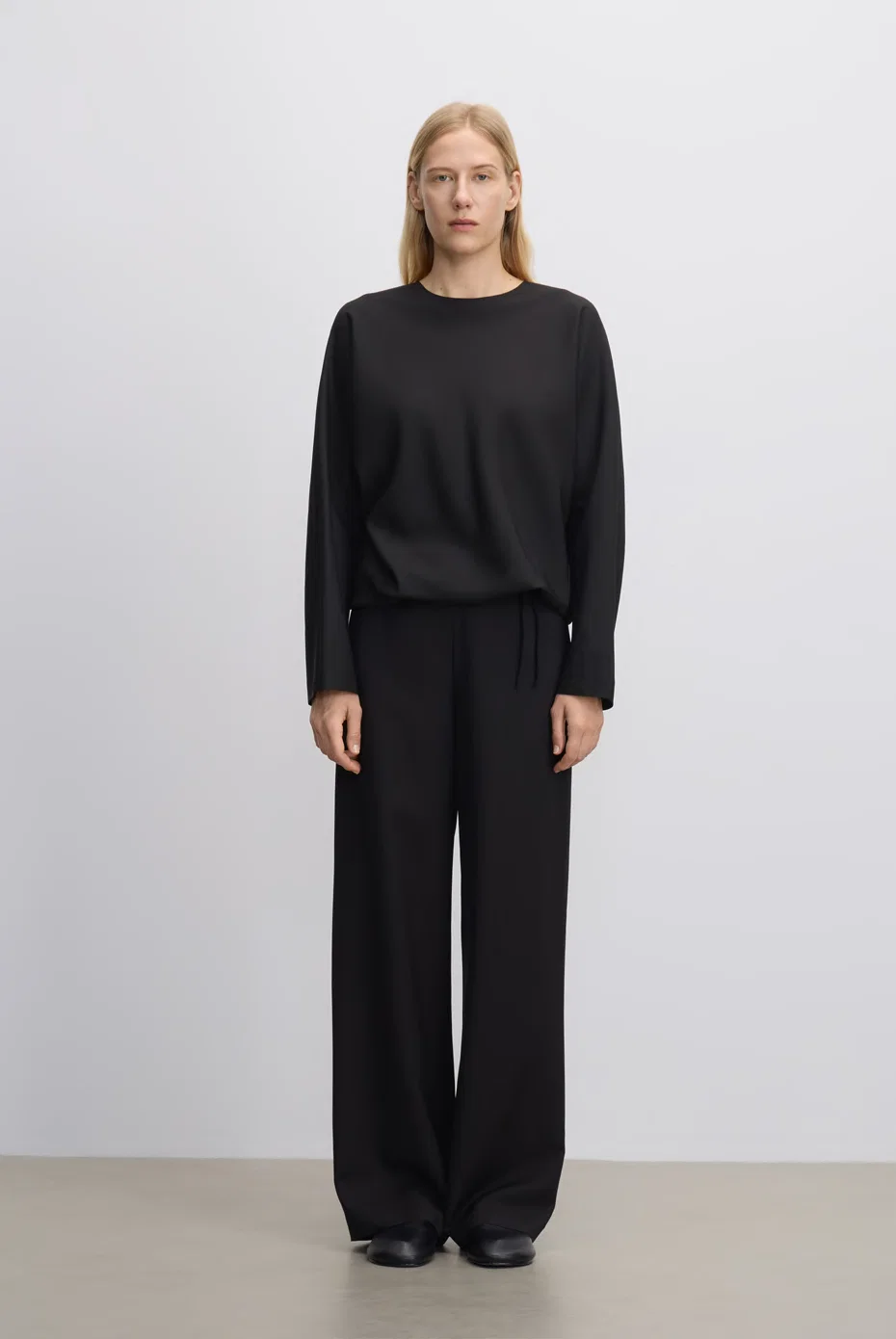 Relaxed black blouse with black wide-leg trousers.