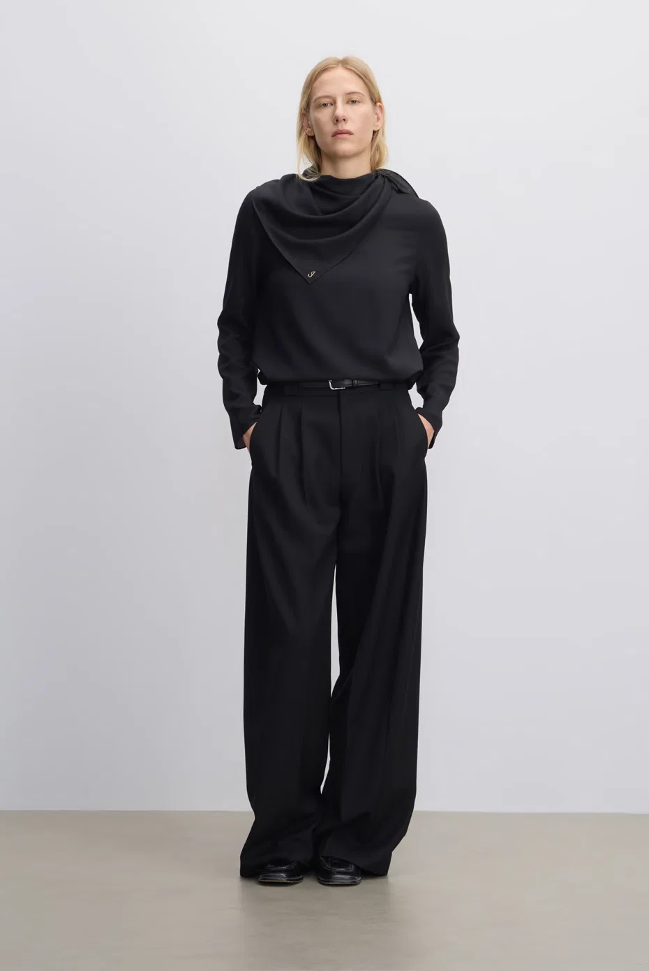 Black draped-neck top with wide black trousers.