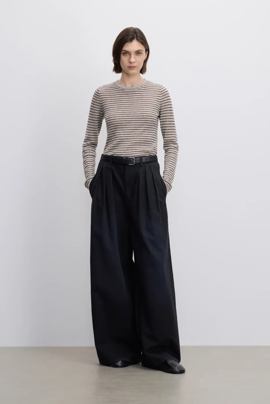 Taupe ruched long-sleeve top with black wide-leg trousers.