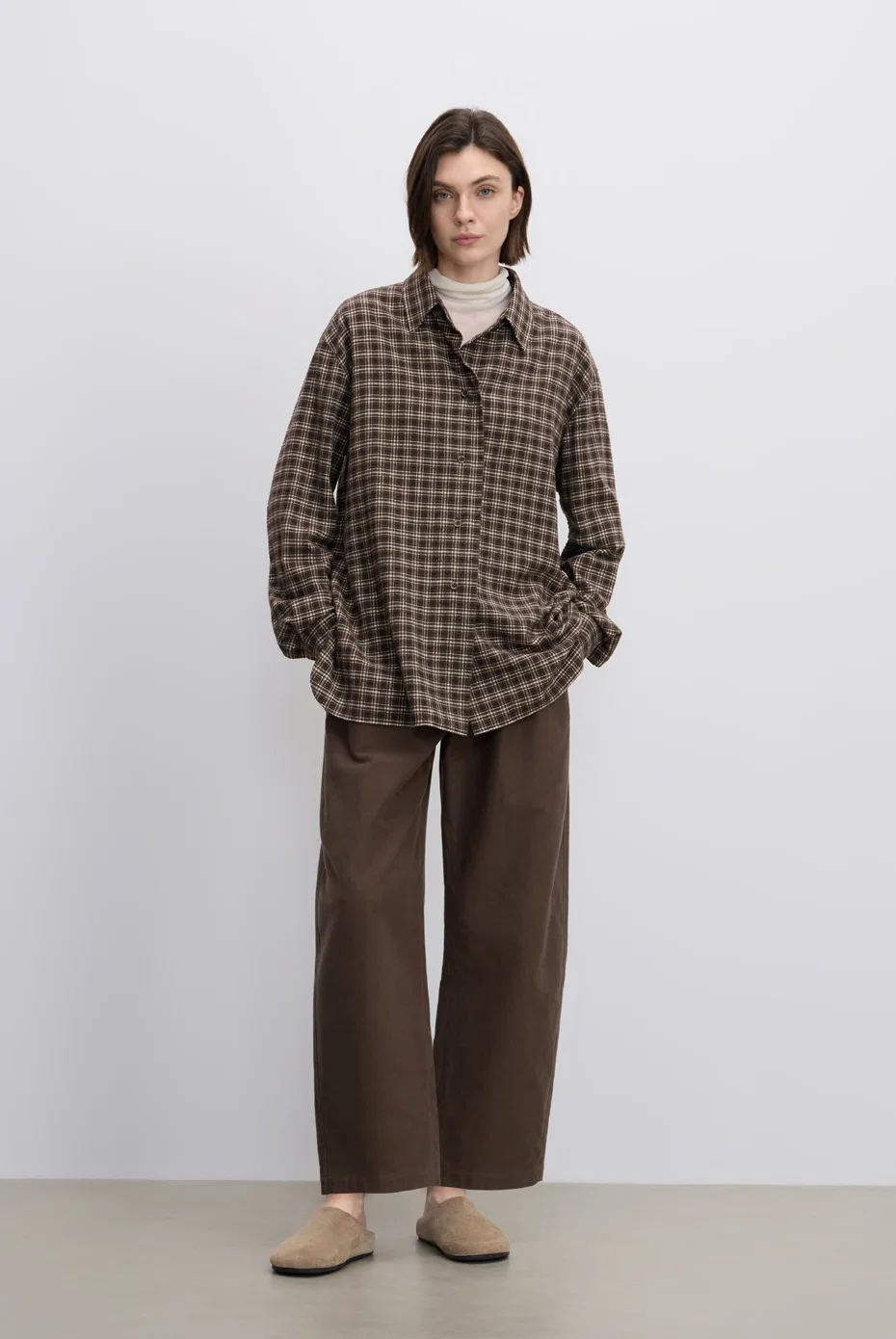 Oversized brown-check shirt with relaxed brown trousers.