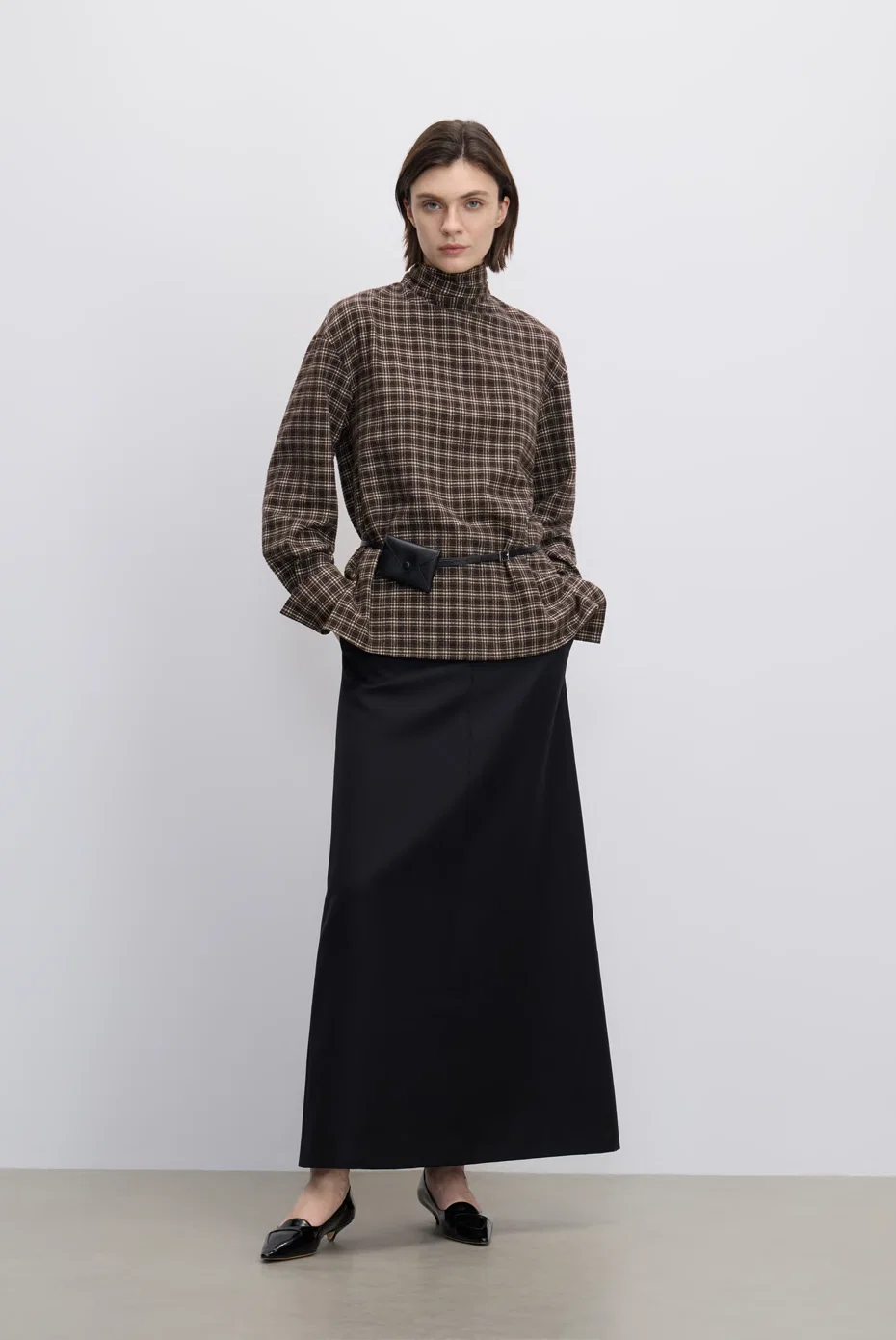 Brown-check high-neck top with a black midi skirt.