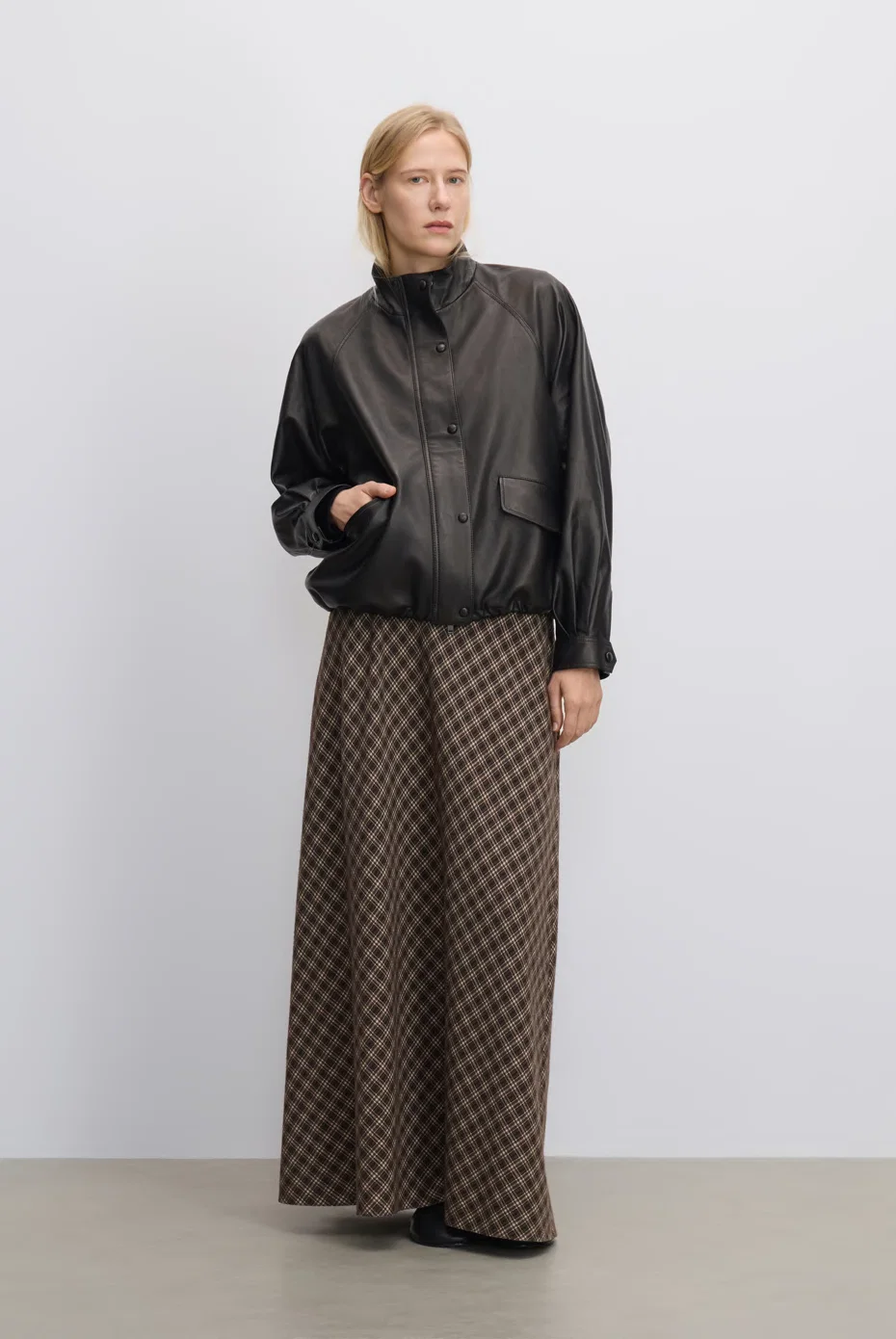 Black blouson with brown-check wide-leg trousers.