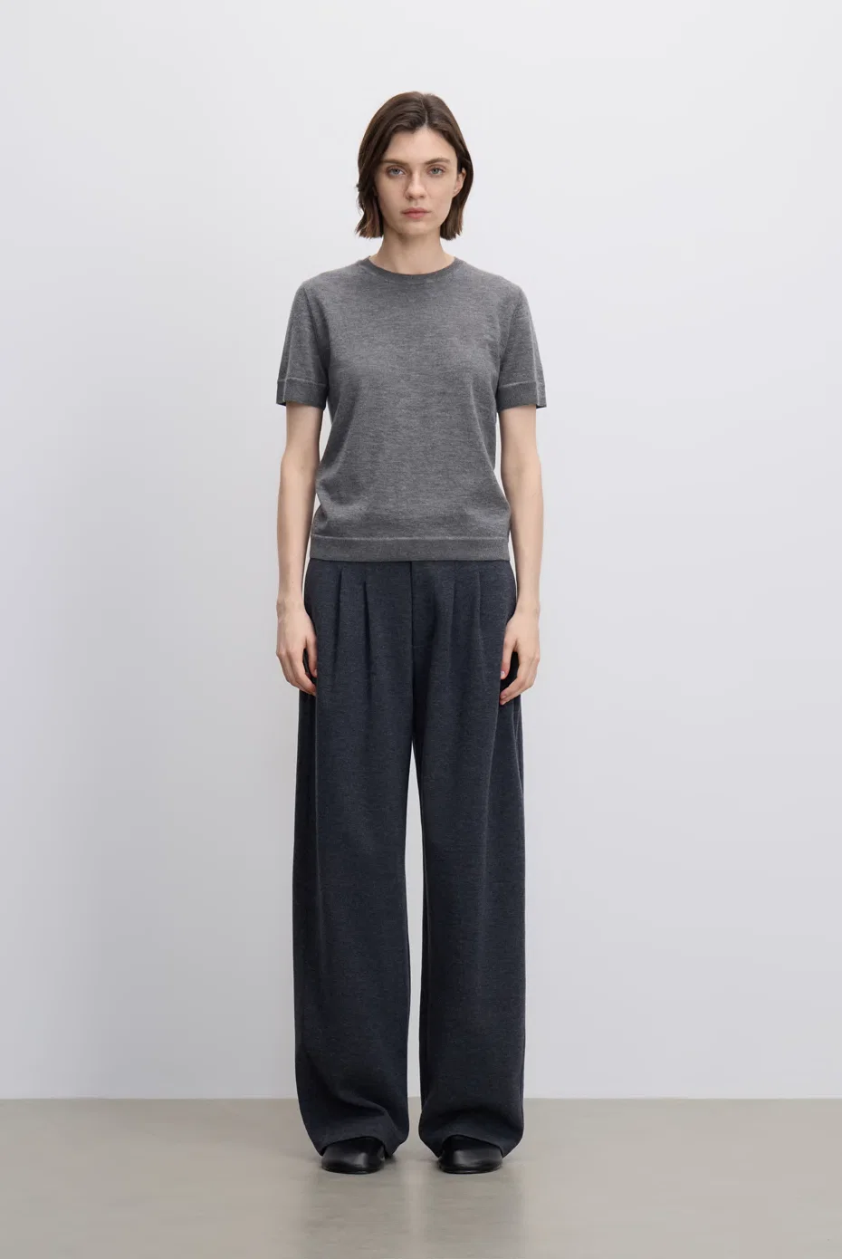 Grey T-shirt with relaxed black trousers.